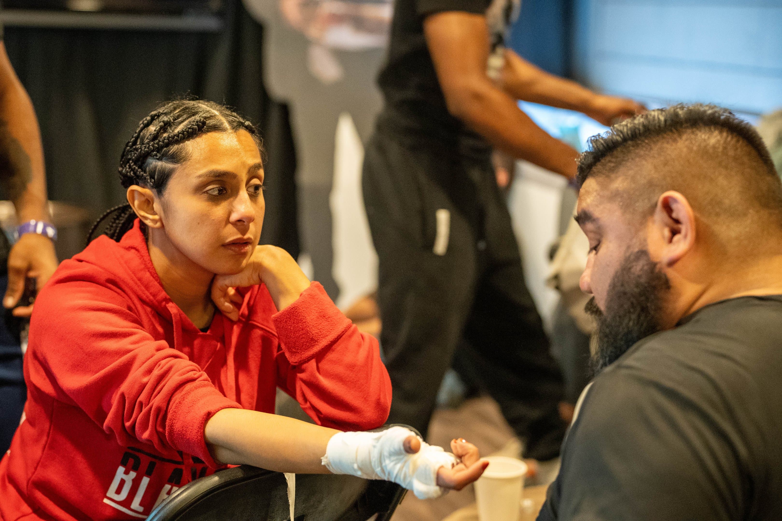 A fighter gets her hands wrapped in the corner before a bout
