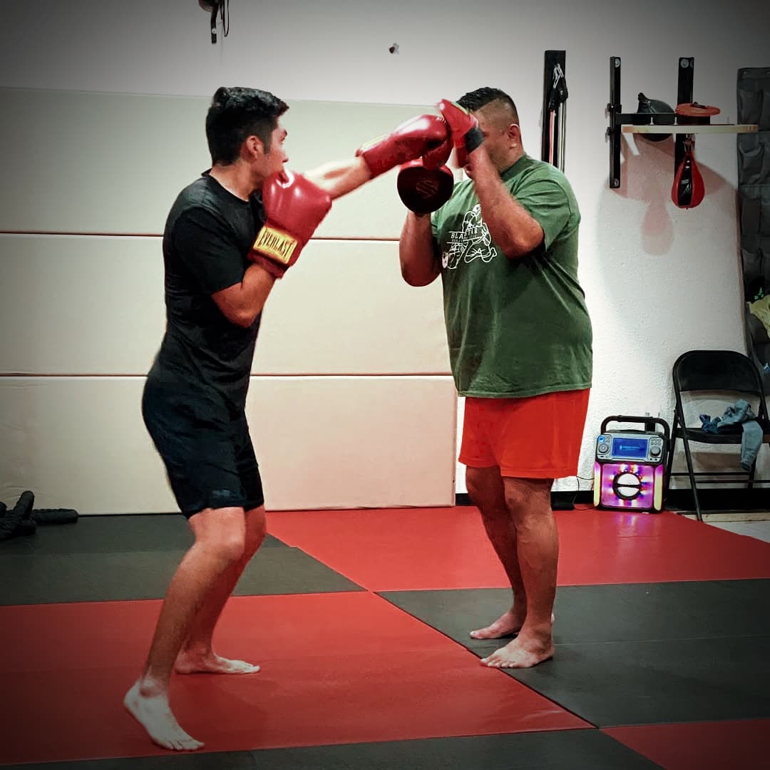 Two training partners drill combinations on the red mats