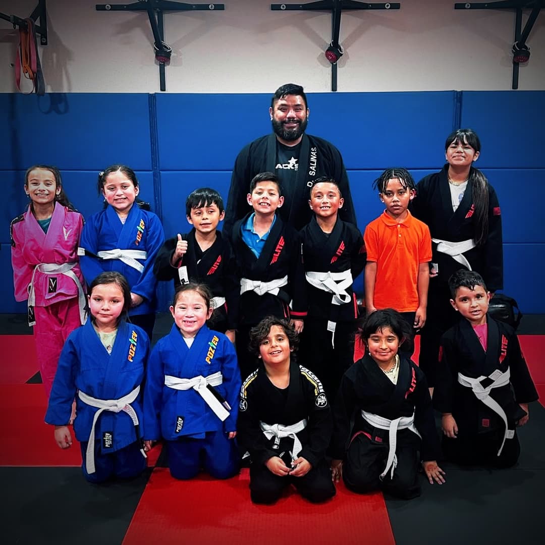 The kids class lines up in their gis with their coaches