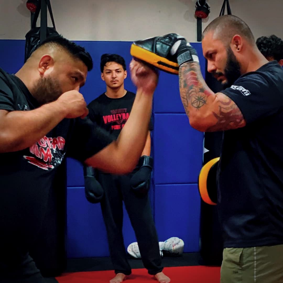 A coach holds pads for a fighter during a late training session
